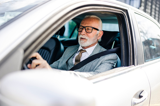 Senior businessman driving a car. About 65 years old, Caucasian male.