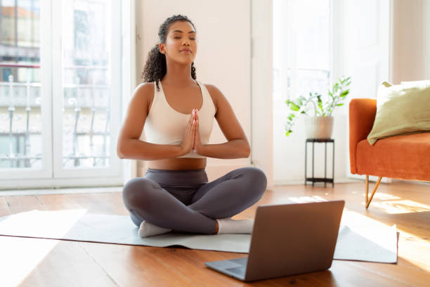 istock lady practicing yoga and meditation in front of laptop indoors 2000480586