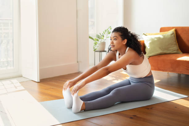 istock woman stretching on mat performing seated toe touch exercises indoor 2000481149