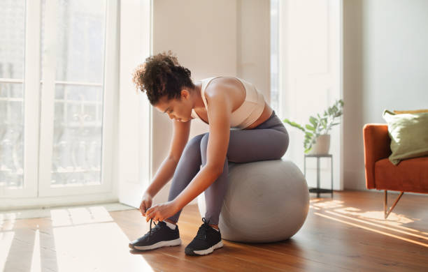 istock lady on exercise ball lacing shoes preparing for training indoor 2000481161