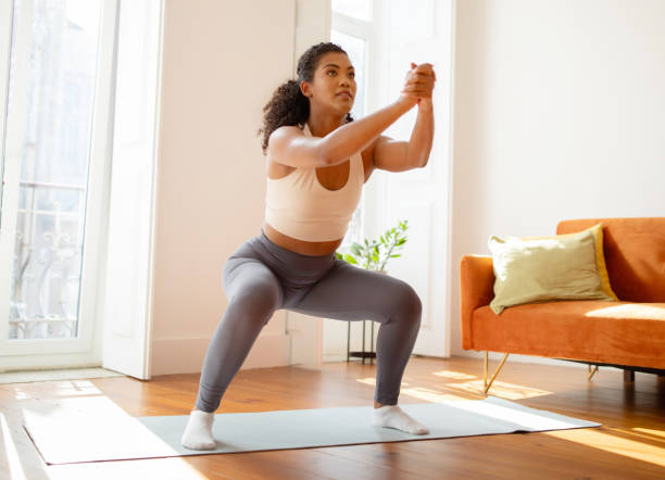 istock fitness woman having domestic workout making deep squats at home 2000481163