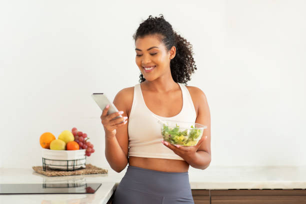 istock fitness lady browsing recipes on smartphone eating nutritious salad indoor 2000481686