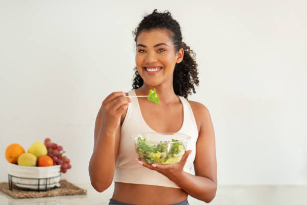 istock Athletic young woman eats veggie salad slimming at home kitchen 2000481693