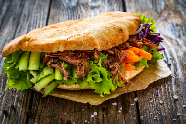 istock Pita - big sandwich with pulled beef and fresh vegetables on wooden table 2000503461