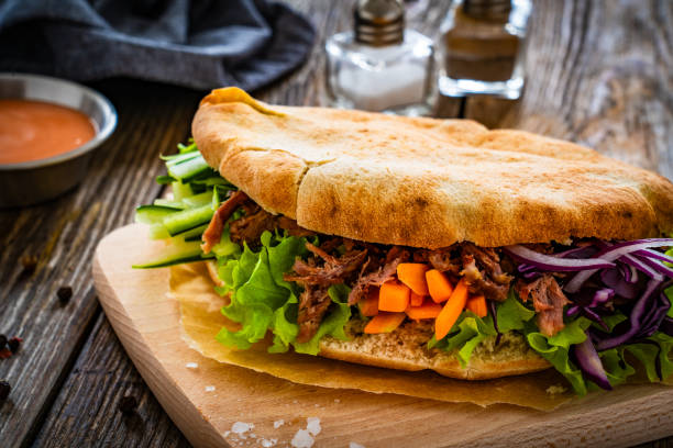 istock Pita - big sandwich with pulled beef and fresh vegetables on wooden table 2000503971
