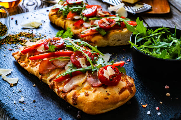 istock Focaccia - roasted mozzarella sandwiches with ham, tomatoes and arugula on black stone plate 2000516039