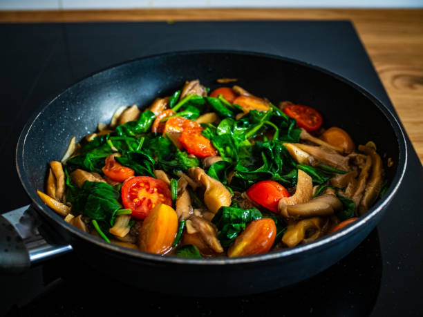 istock Oyster mushrooms with spinach and tomatoes in frying pan 2000518172