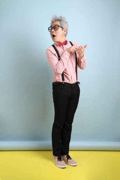 Valentine's Day Asian senior man in black suspenders with red bow with gesture of Note-taking and plagiarism isolated on blue background. St Valentine's Day middle eastern ethnicity mature adult book reading stock pictures, royalty-free photos & images