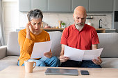 Financial Crisis. Stressed Senior Couple Checking Documents At Home