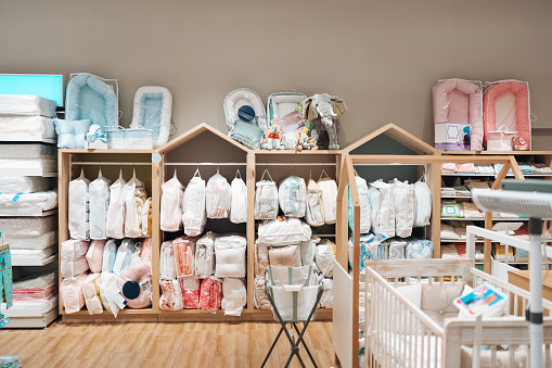 Beautiful baby clothes hanging arranged on rack in a modern store or shop. Shopping interior  concept. No people.