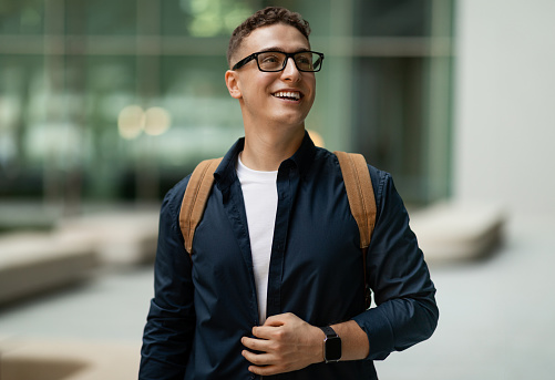 Glad shocked young european man student in glasses with backpack enjoy lifestyle, look at free space in city, outdoor. Work, business, study and education, ad and offer, sale