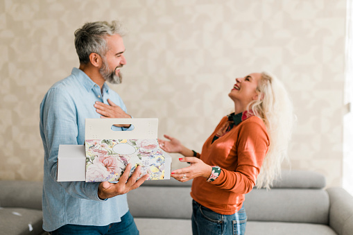 Husband at home surprising his  wife with a gift