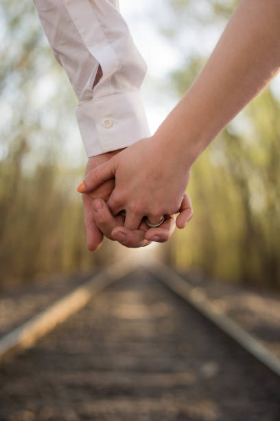 istock Couple holding hands while standing on a railroad track 2000538226