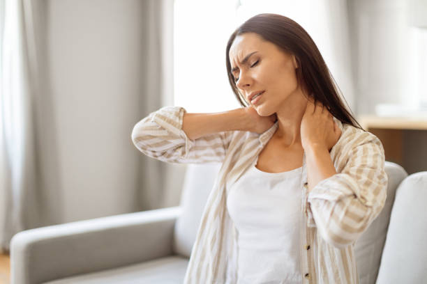 istock Young woman at home touching her neck with pained expression, 2000547228