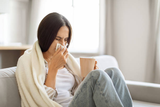 istock Young woman feeling sick at home, blowing her nose with tissue 2000547230