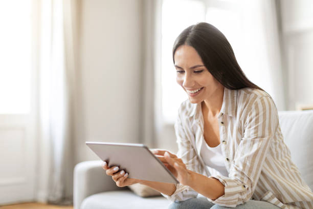 istock Cheerful young woman engaged with her digital tablet at home 2000547741
