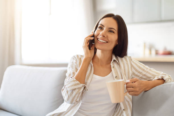 istock Pleasant Call. Happy Woman Talking On Phone And Drinking Coffee At Home 2000547766