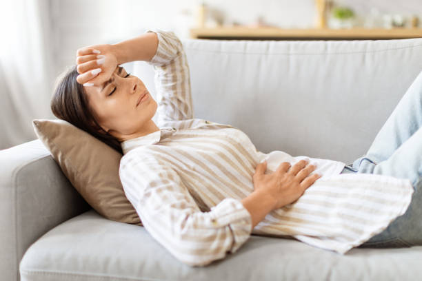 istock Sick young woman lying on couch, feeling unwell at home 2000547794