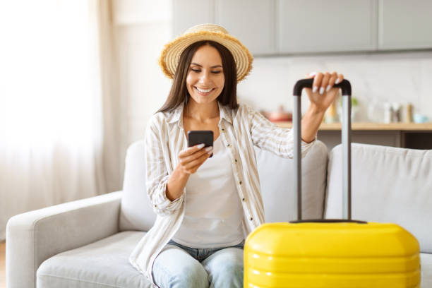 istock Smiling Young Woman Using Smartphone For Booking Vacation Online 2000548319