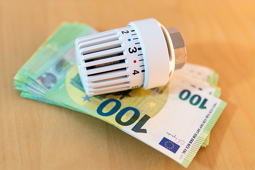 Heating thermostat lies on banknotes - the concept of high heating costs