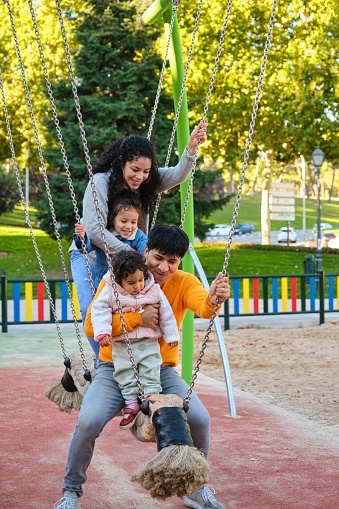 Hispanic family with two children playing together in a playground. Latin family.