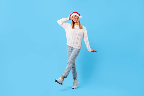 Happy woman in Santa hat posing on blue background