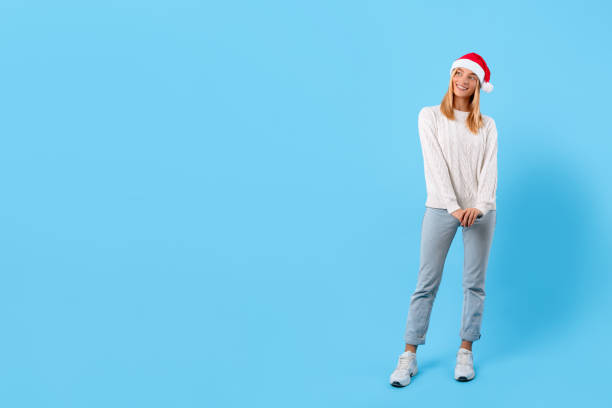 istock Happy woman in Santa hat posing on blue background, free space 2000596482