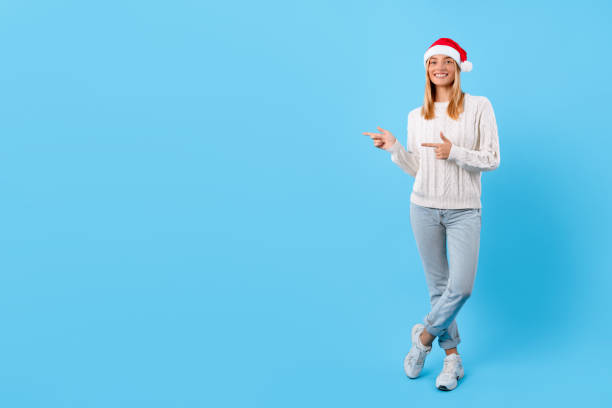 istock Cheerful woman with Santa hat pointing away at free space 2000596490