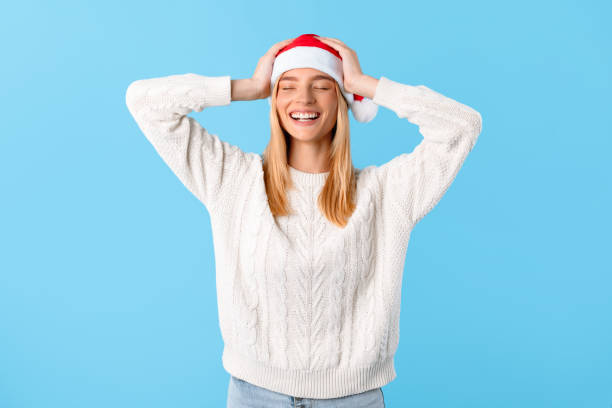 istock Joyful woman in Santa hat on blue background 2000597047