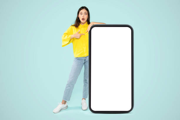 istock Amazed young woman posing by huge phone, mockup 2000620007
