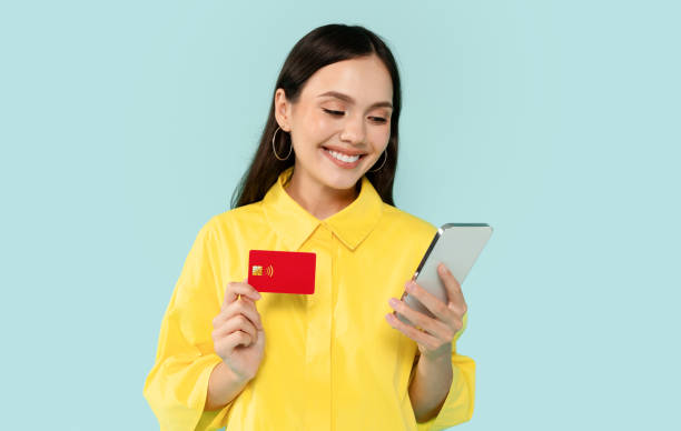 istock Happy young woman using cell phone and credit card 2000620021