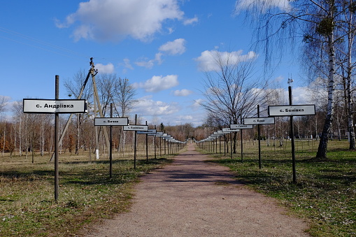 Alley with the names of abandoned villages in the zone of the Chernobyl nuclear disaster. Memorial complex to resettled villages in Exclusion Zone. Signposts with names of villages in Cyrillic.