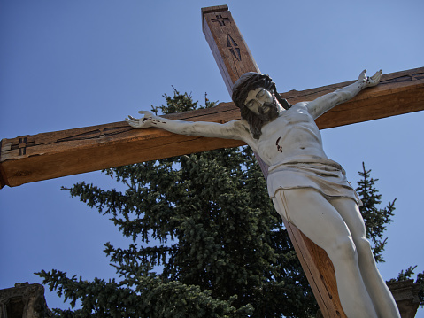 A sculptural image of the crucified Jesus Christ against a clear sky. Bottom view. Crucifixion.