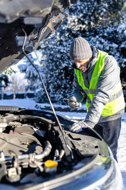 istock Man in safety vest using mobile phone to call roadside assistance. Car breakdown winter scene concept. 2000634405