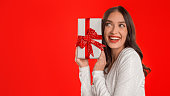 Woman Celebrating Posing with Gift Box on Red Studio Background