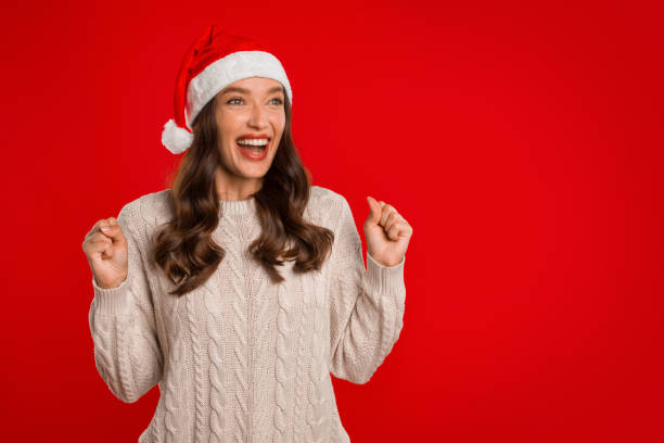 istock Woman In Santa Hat Celebrating Success On Red Studio Background 2000639149