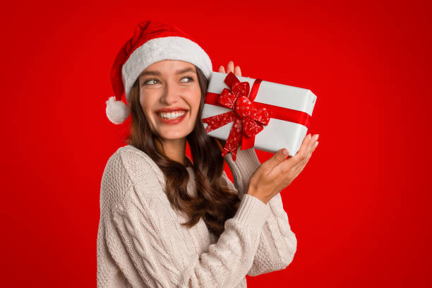 istock Smiling caucasian woman in Santa hat holds box gift, studio 2000639154