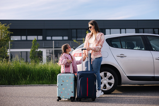 Adorable daughter with her mom go to airport with suitcases. Two girls goes to a trip. Little girl travel with mom. High quality photo