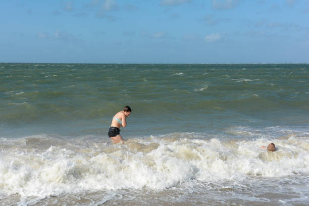 istock Two children have fun in the waves on the sea beach 2000651847