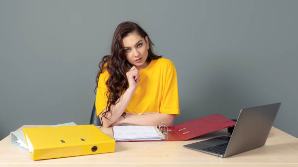 young business woman with long dark hair working with document in office, isolated on gray background - paper document pen long hair photos et images de collection