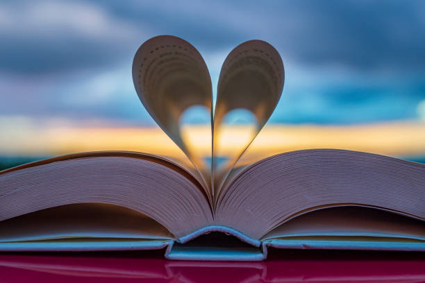 istock Heart silhouette with an open book at sunset 2000662396