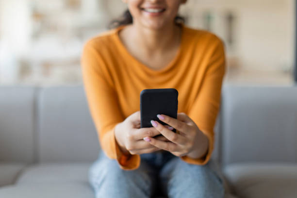 istock Closeup Shot Of Smiling Young Female Using Smartphone At Home 2000663523