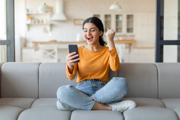 istock Joyful young indian woman with smartphone celebrating victory 2000663610