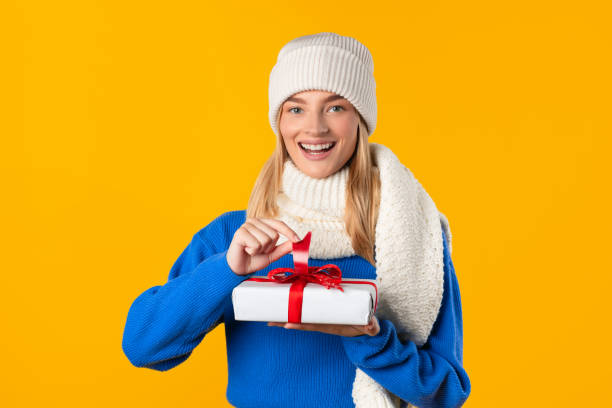 istock Smiling european woman unwrapping red-ribboned gift 2000665174