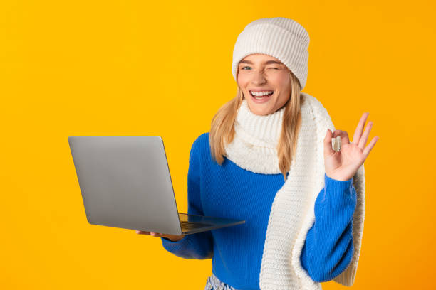 istock Joyful woman in blue sweater with laptop making OK sign 2000665194