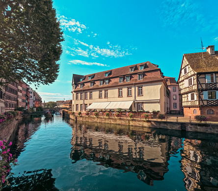 Looking out over a canal to historical medieval architecture in Strasbourg, France on a beautiful Summer day. Located in the La Petite area. A UNESCO World Heritage Site.