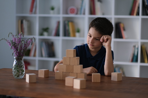 Little boy stacking wooden cubes