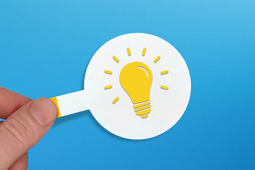 Creative idea, inspiration, new idea and innovation concept. Lightbulb sign on sticker note paper with blue background.