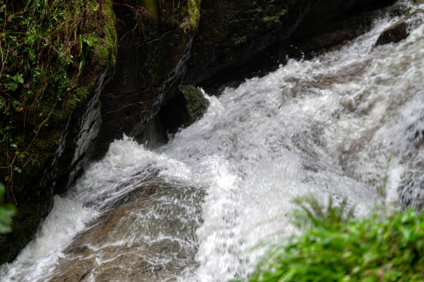 Rapid and powerful water flow between large rocks in cold mountain river, close-up