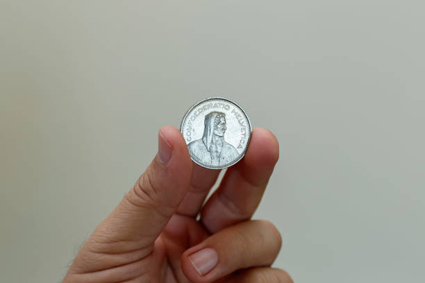 swiss five franc coin between fingers - swiss franc coin